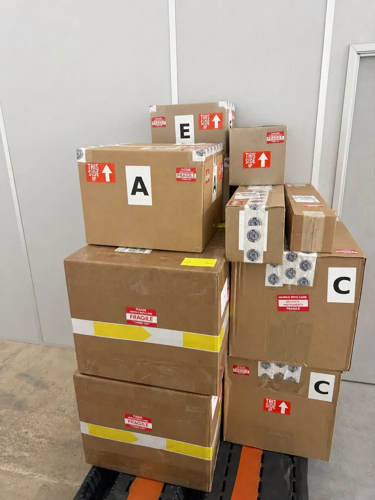 Packed boxes stacked on a pallet, marked fragile, this side up and lettered by position
